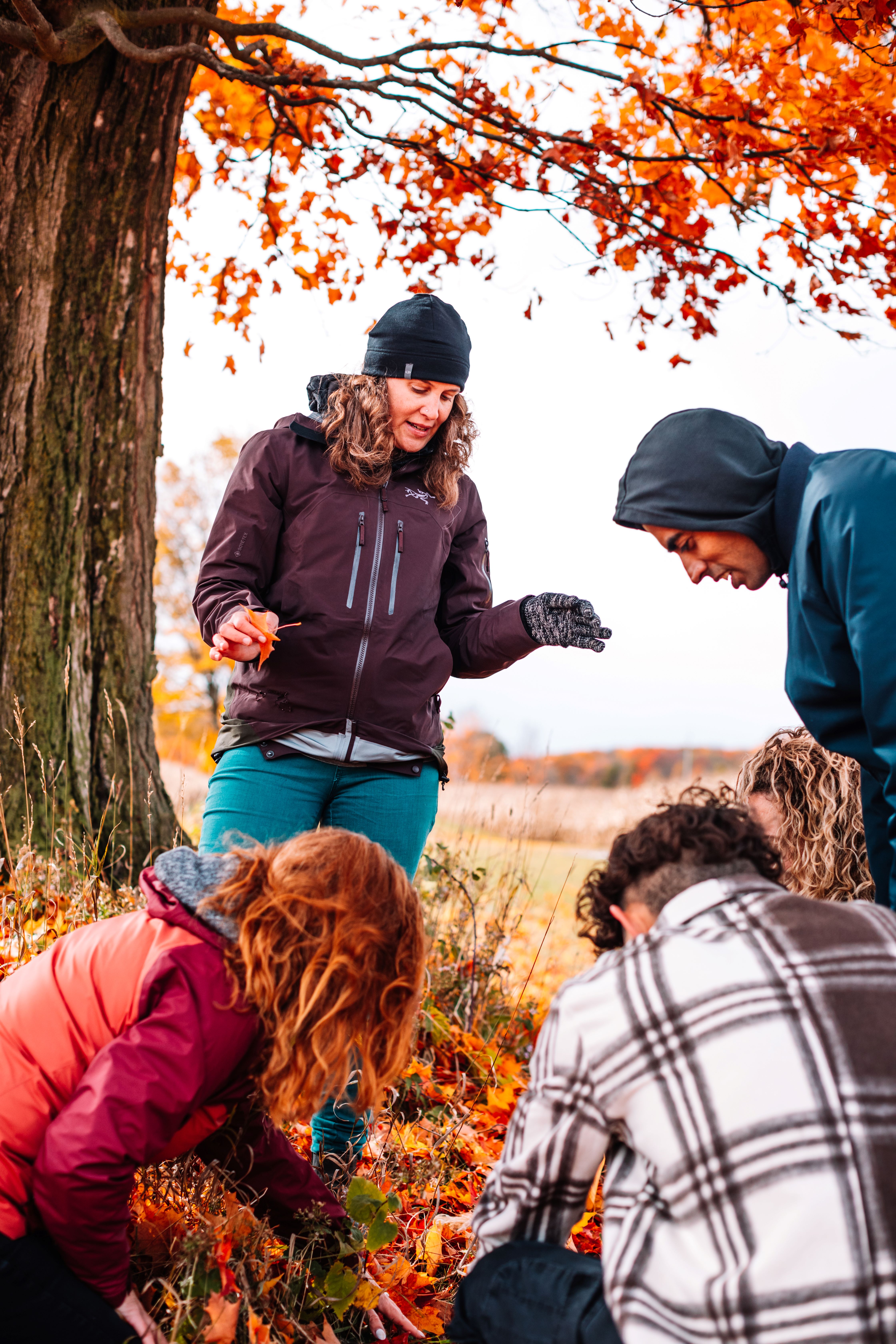 Dr. Ellen Field outdoors with students looking at autumn leaves