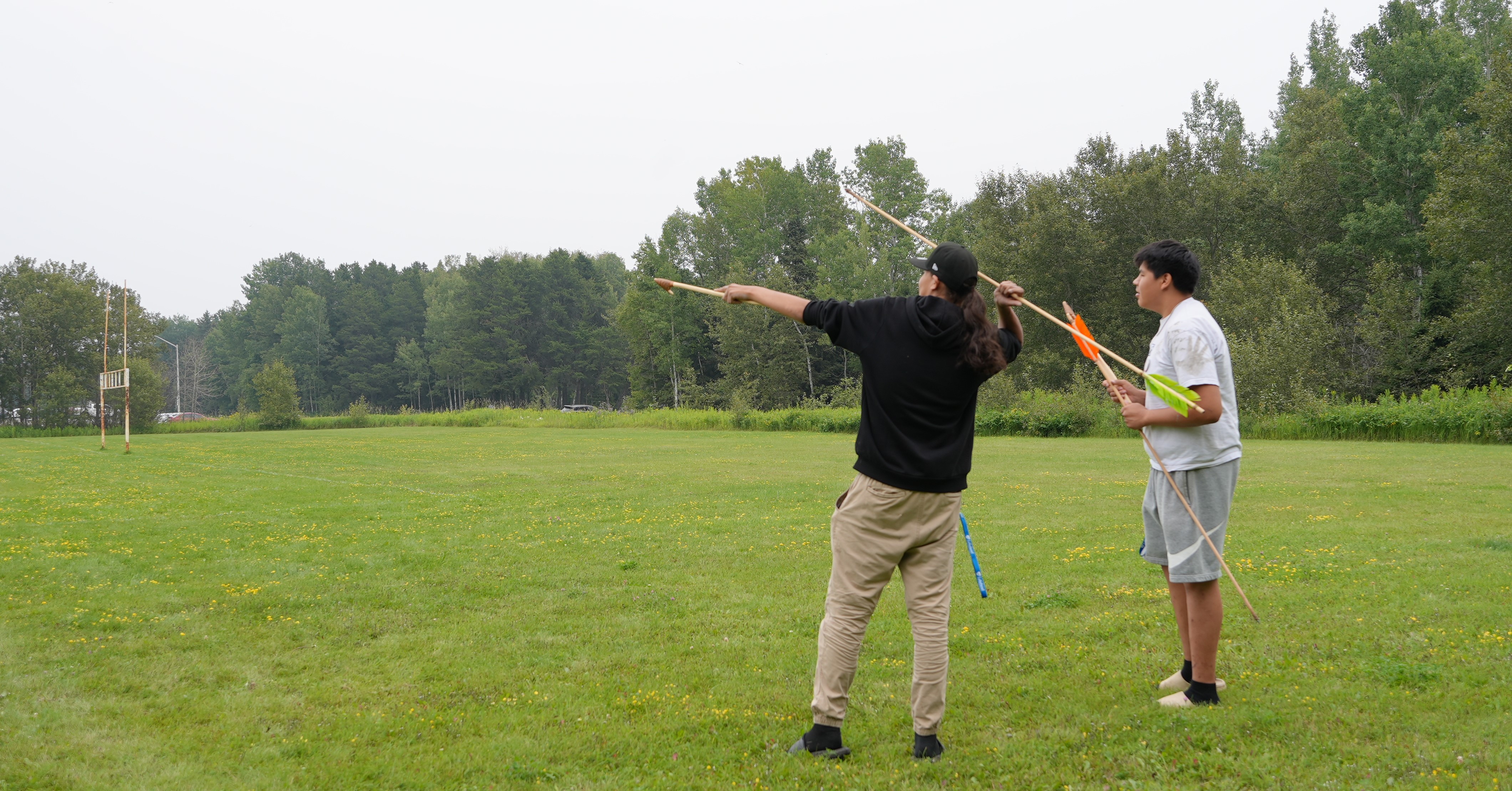 Two Outland students prepare to throw spears as part of experimental archaeology programming near Lakehead's Fieldhouse