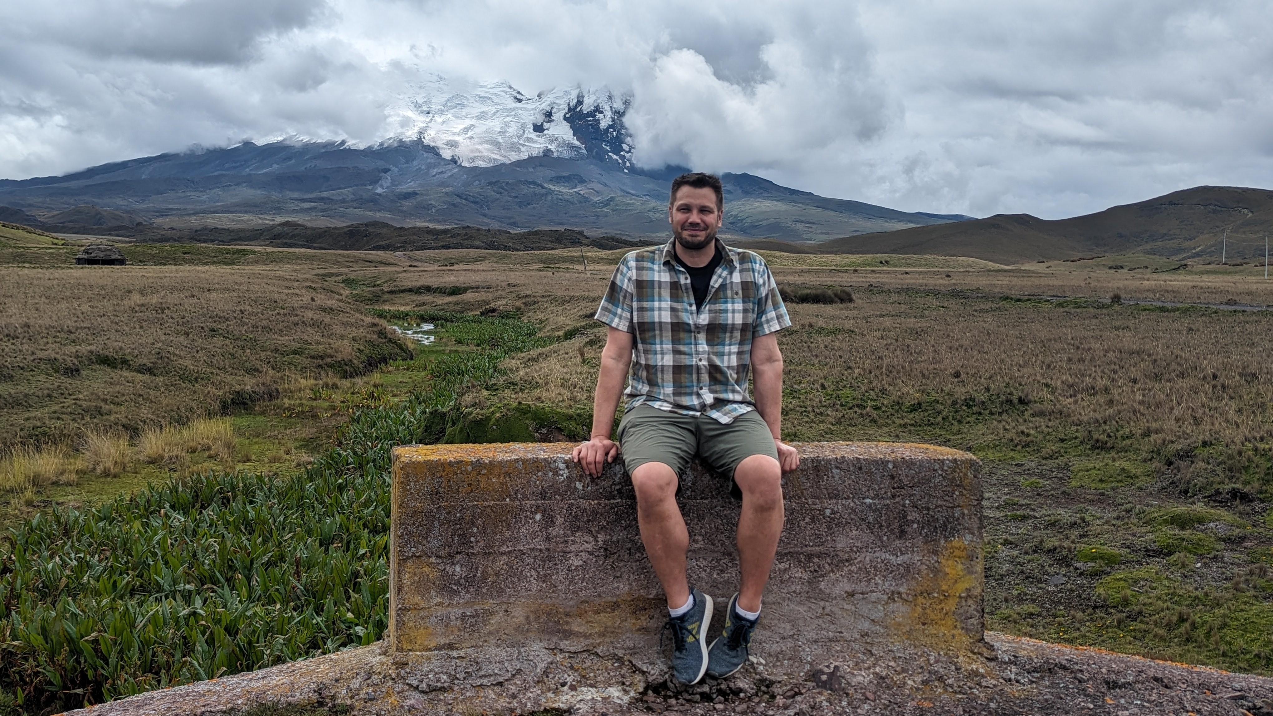 Dr. Nathan Basiliko sits on a stone wall near the Antisano Volcano in Ecuador