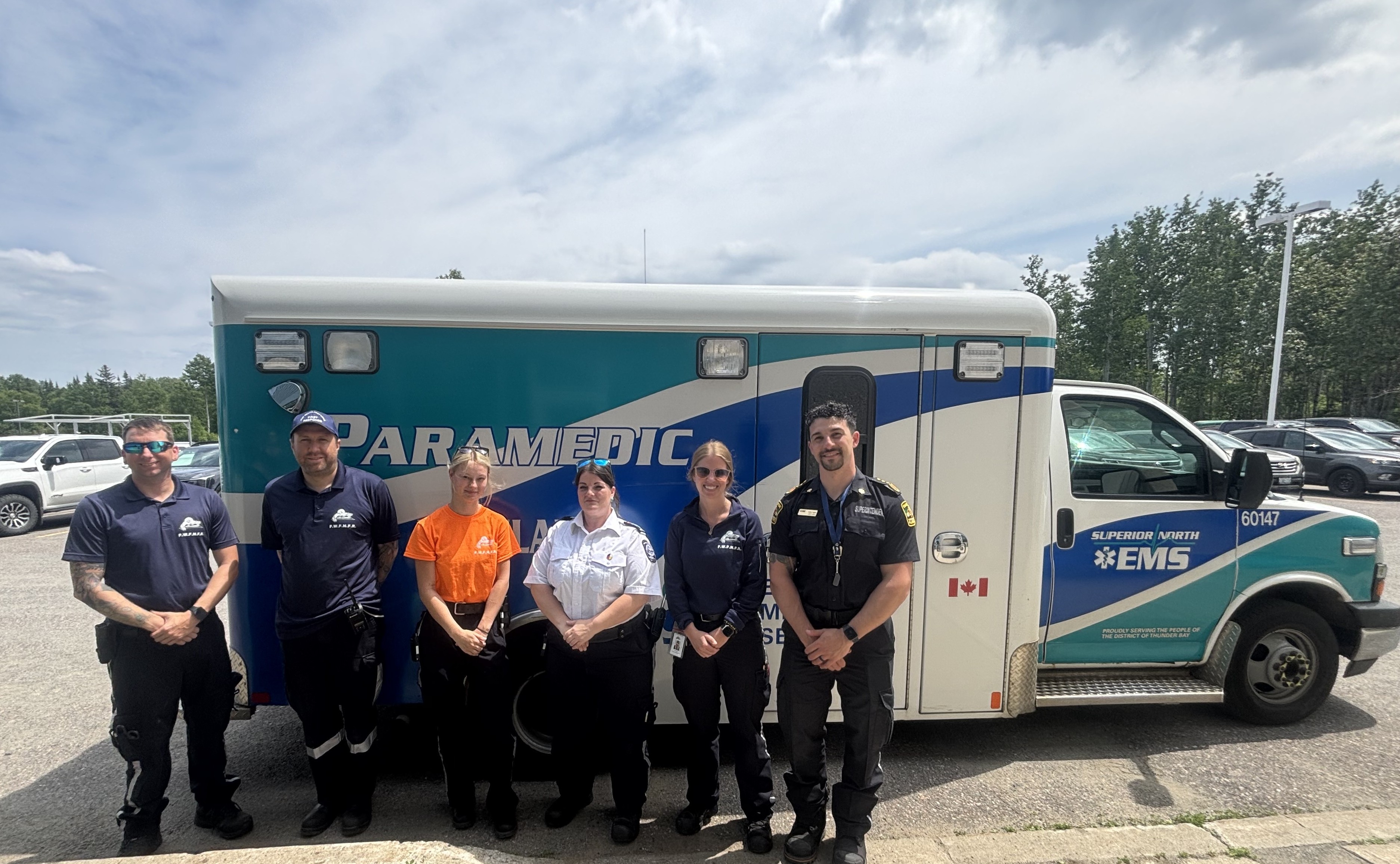 Erin Christiansen and fellow members of the Fort William First Nation Medical First Response Team stand in front of Superior North EMS paramedic vehicle in a parking lot