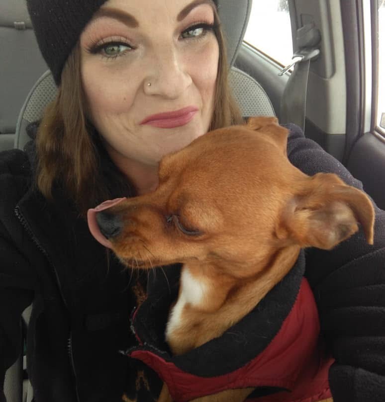 Erin Christiansen in a vehicle with her dog Tiny in her lap
