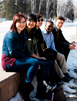 Students sitting together on a bench posing for the photo