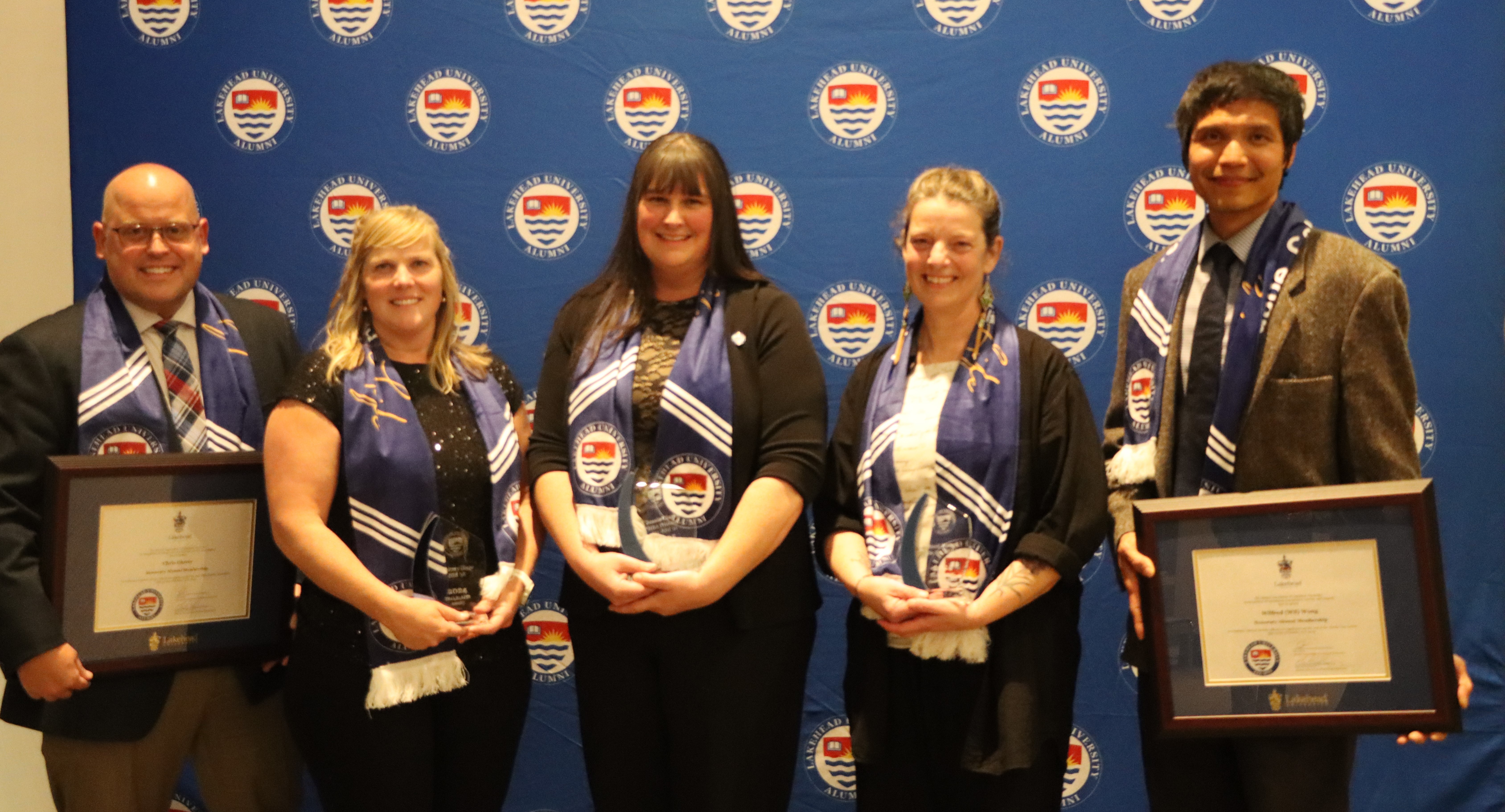 Heidi Warren and other Lakehead Orillia alumni award winners stand together while holding their awards