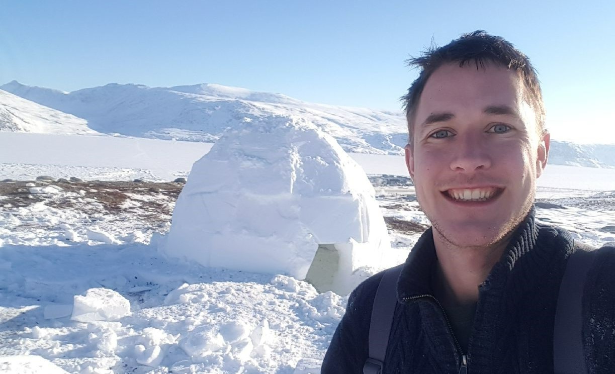 Ian McRae standing by an igloo and smiling