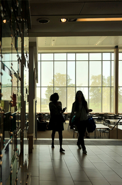 A photo of two students walking across a hallway on Campus
