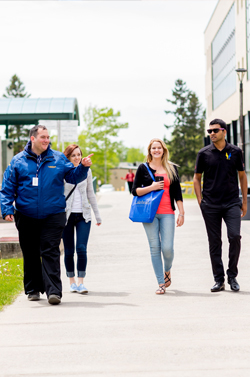 A photo of a member of our staff with students showing them around campus