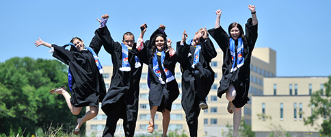 Students in their grad gowns jumping for joy