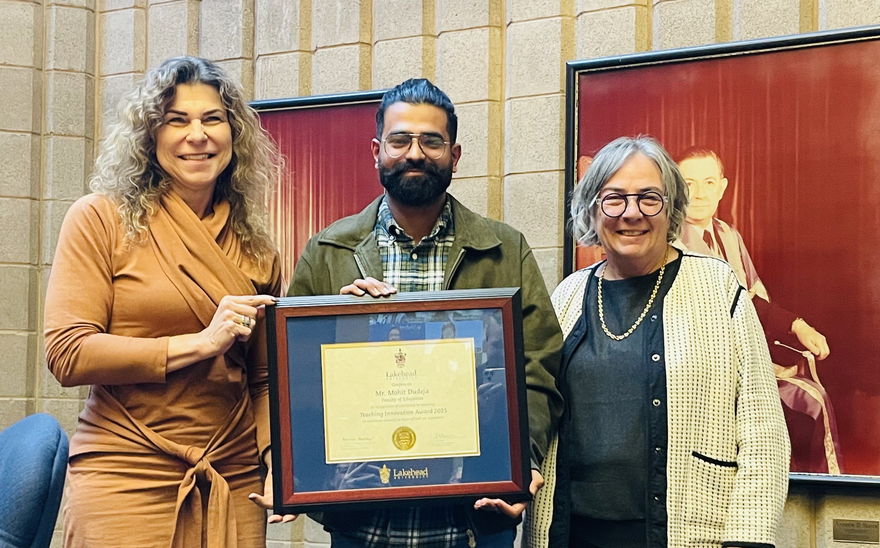 Mohit Dudeja, flanked by Dr. Gillian Balfour and Dr. Gillian Siddall, holds his framed 2025 Teaching Innovation Award in Lakehead's Senate Chamber