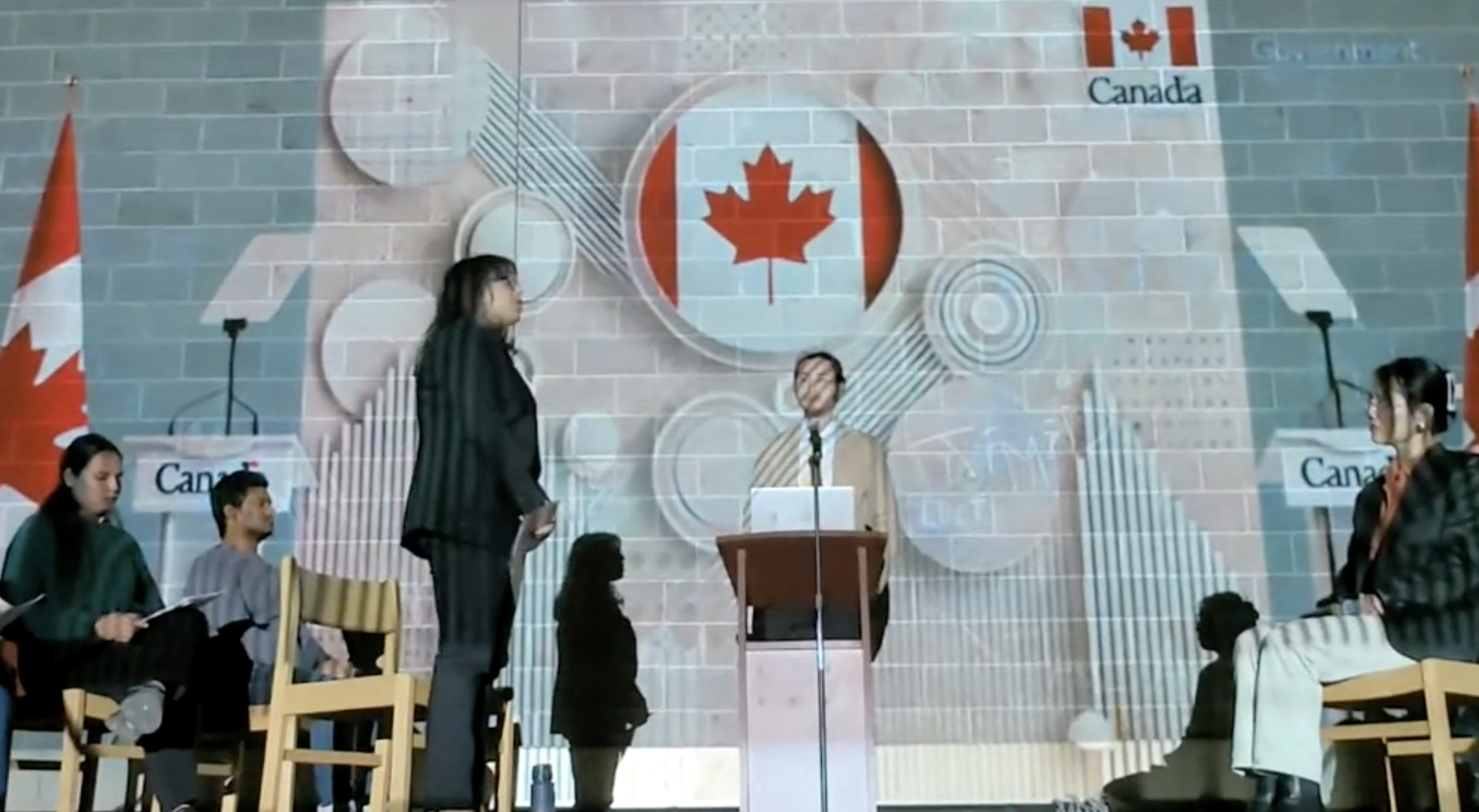 Lakehead students perform the last scene of their play for the Activism in Education play with images of the Canadian flag projected onto the wall of the auditorium
