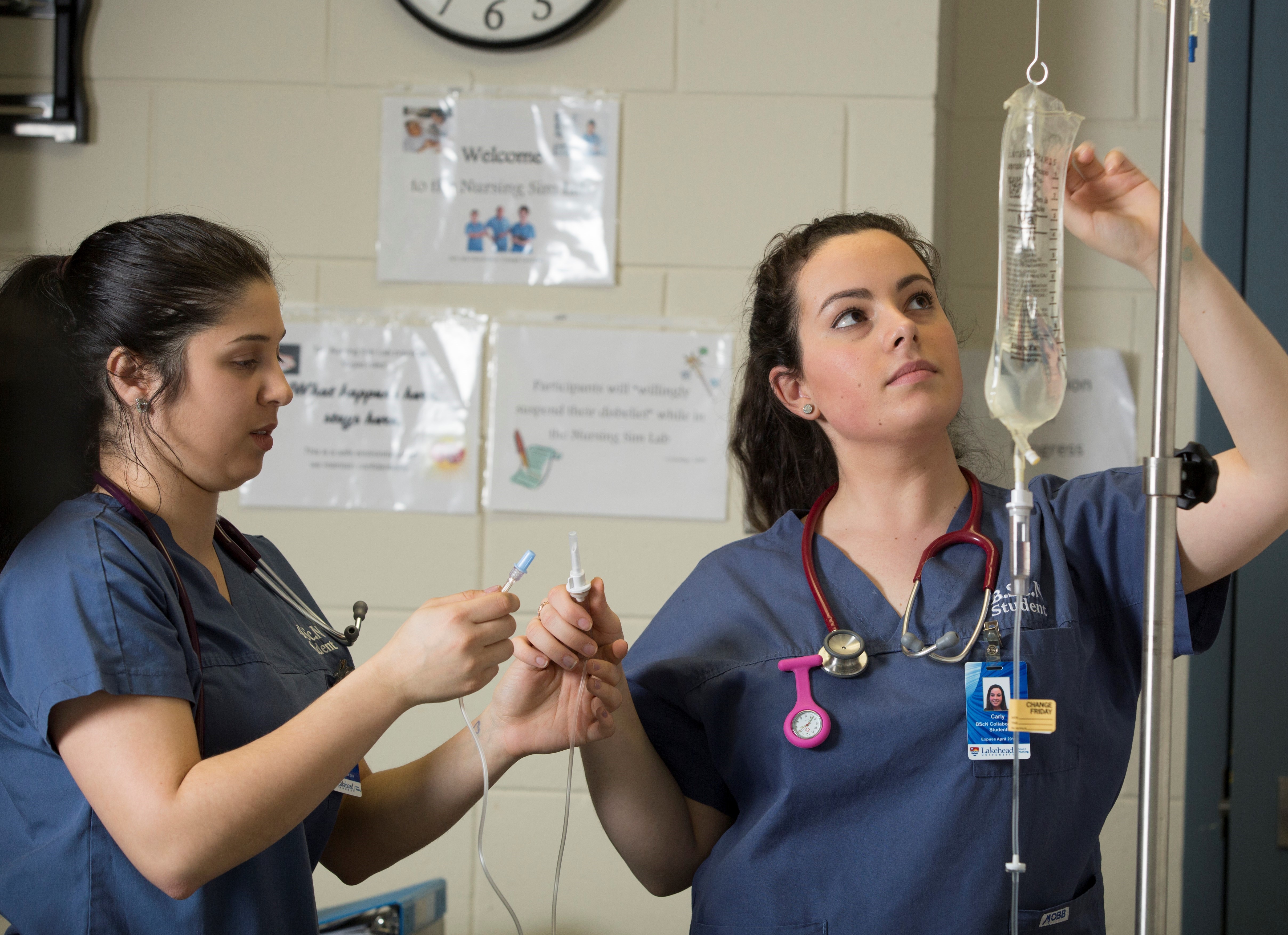 Two nursing students adjust an IV lab in nursing simulation lab