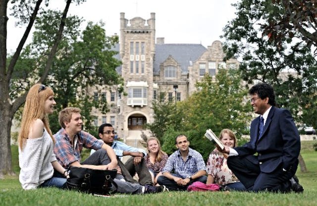 Students sitting in grass in front of Bora Laskin Faculty of Law building