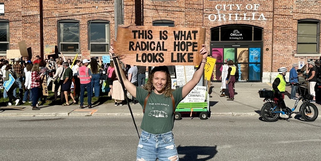 Sidney Howlett holds a sign saying "This Is What Radical Hope Looks Like" at a climate protest