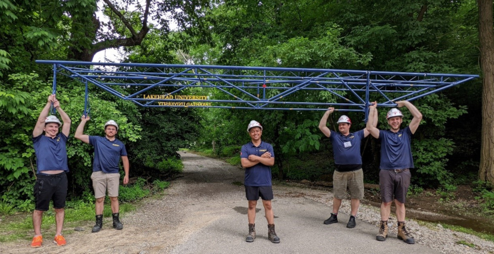 Photo of the Steel Bridge Team holding the bridge above their heads.