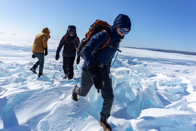 Teigan Labor, wearing winter clothing and a backpack, hikes with two other people across Lake Superior in the winter