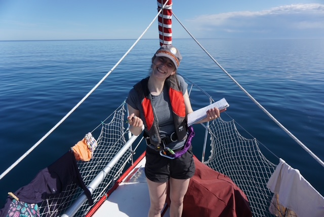 Teigan Labor on a sailboat holding a notebook and a pen