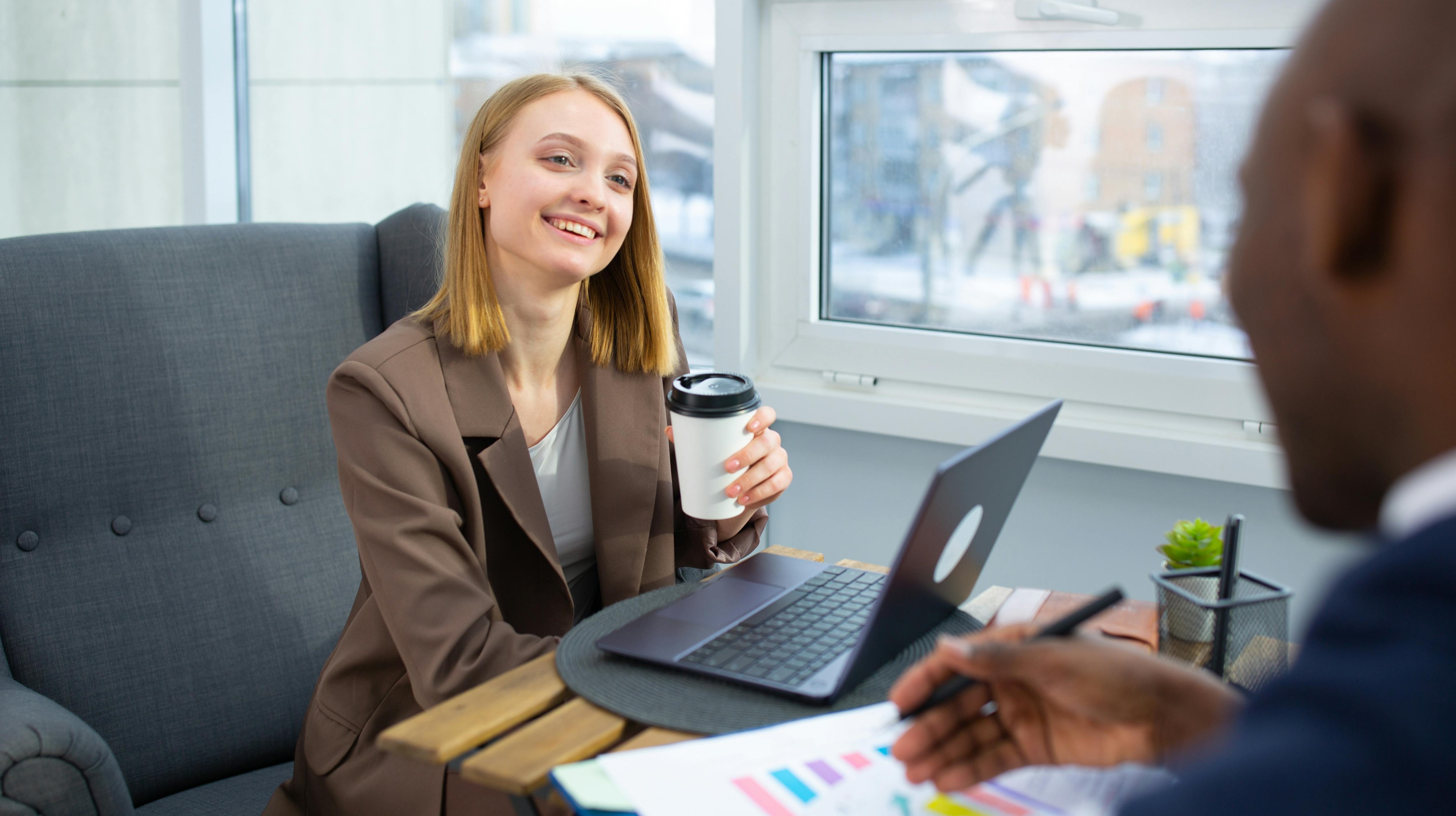 Coffee Break A young career woman drinking coffee while sitting at a table with a male colleague