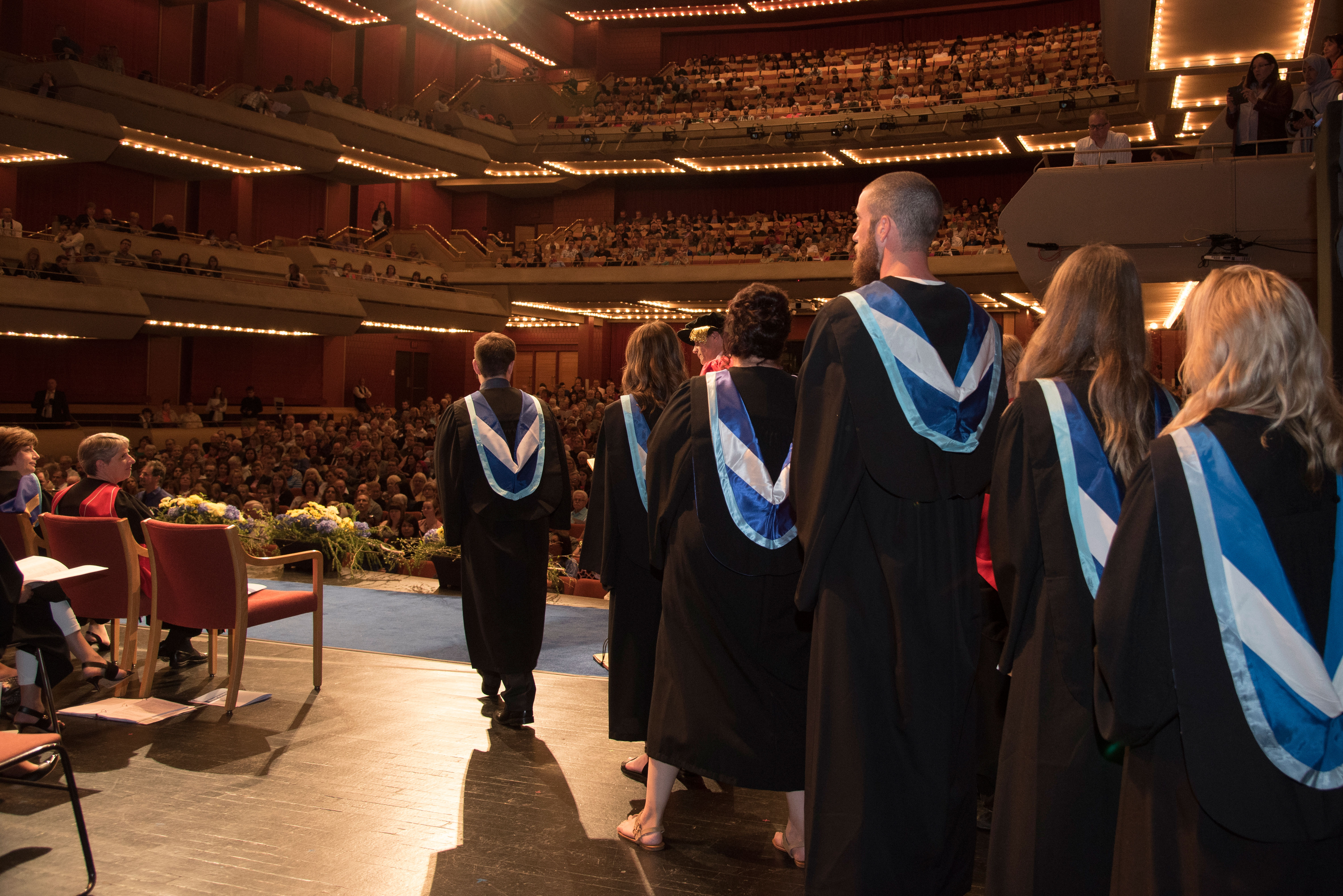 Back view of Lakehead grads walking onto the stage at a convocation ceremony