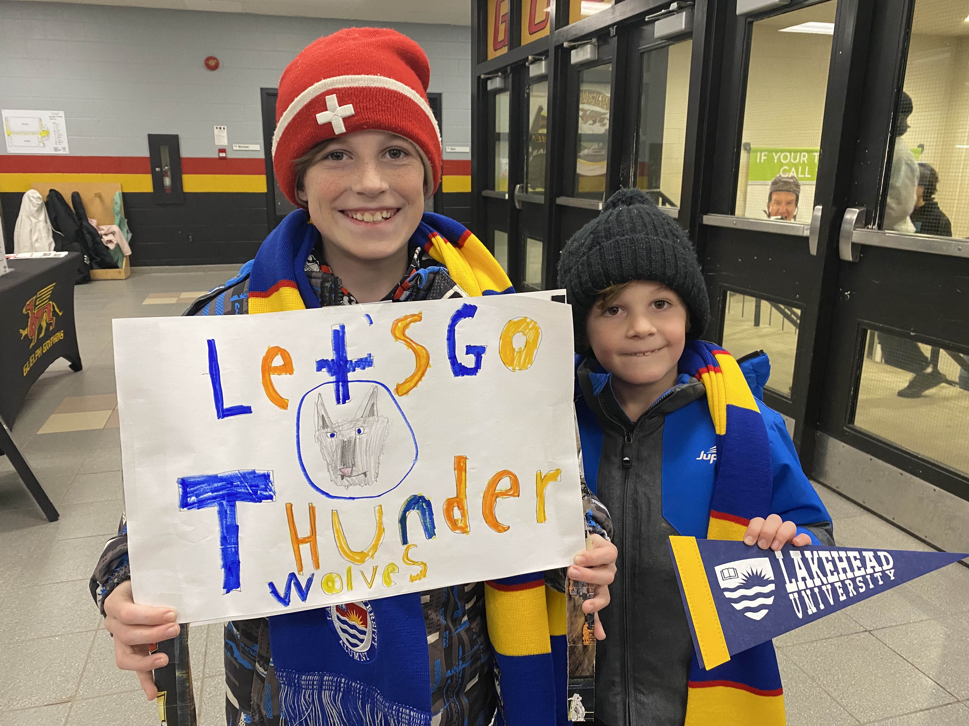 Youngsters Elliot and Cohen Kaesermann wearing Thunderwolves gear and holding a Let's Go Thunderwolves sign