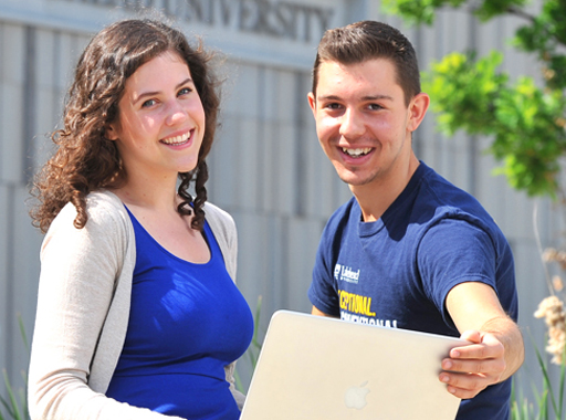 Two students smiling with a laptop outside on Orillia campus