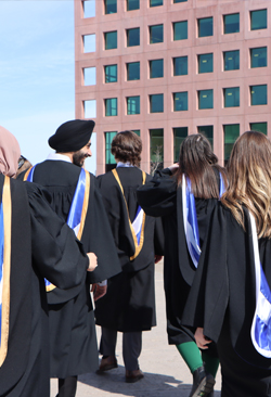 A photo of students in grad gowns walking towards a building