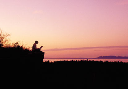 Female sitting on the edge of a cliff with a laptop