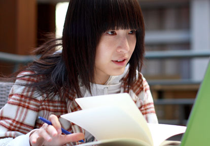 Female student flipping through a notebook while holding a pen