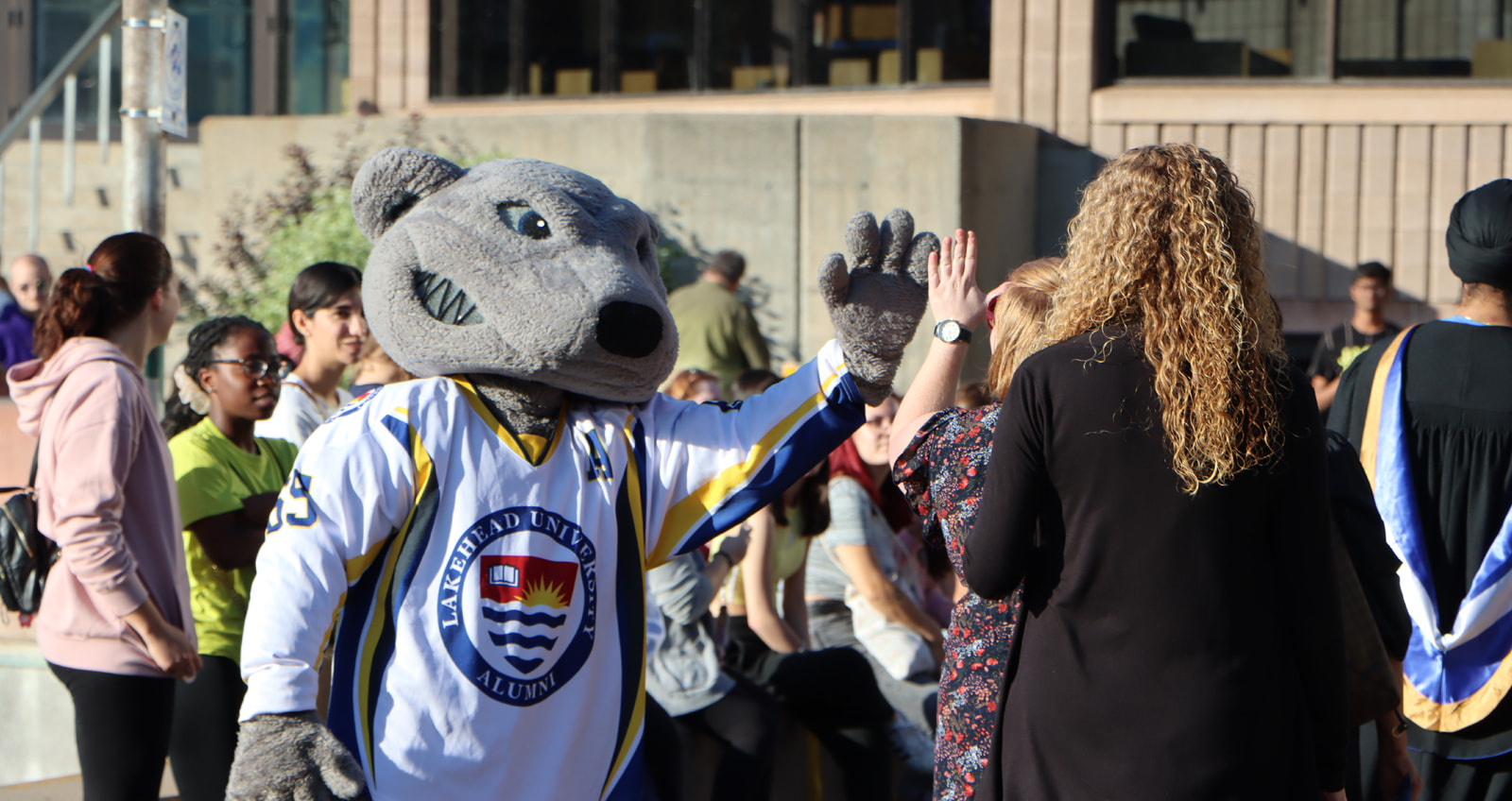 Lakehead University Mascot Wolfie high fiving a first year student at an orientation event