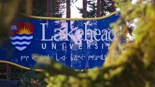 Lakeheads signage outside the thunder bay campus, shrouded by some foliage