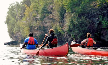 a group of people canoeing beside a rock face