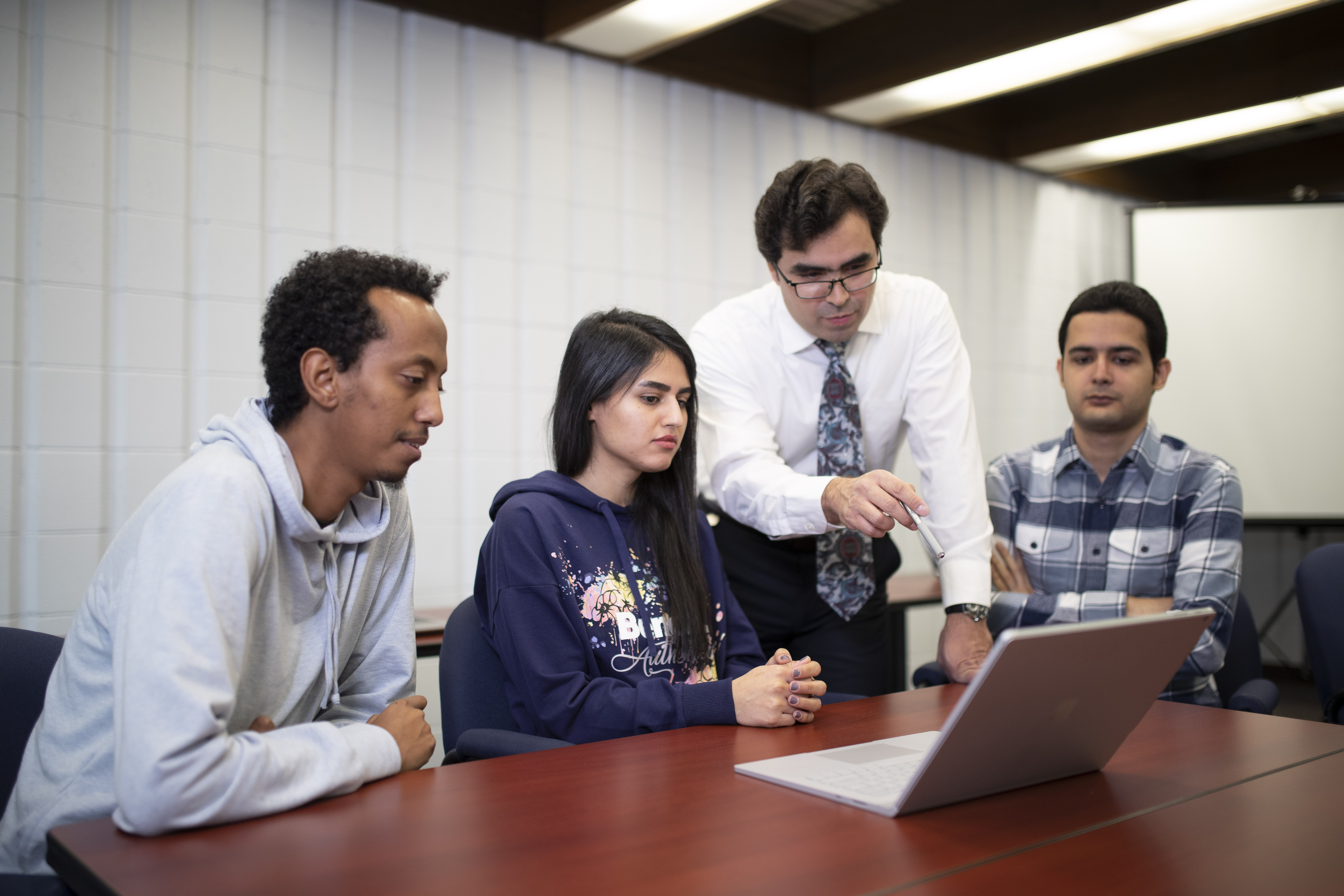 Instructor with three students looking at a laptop