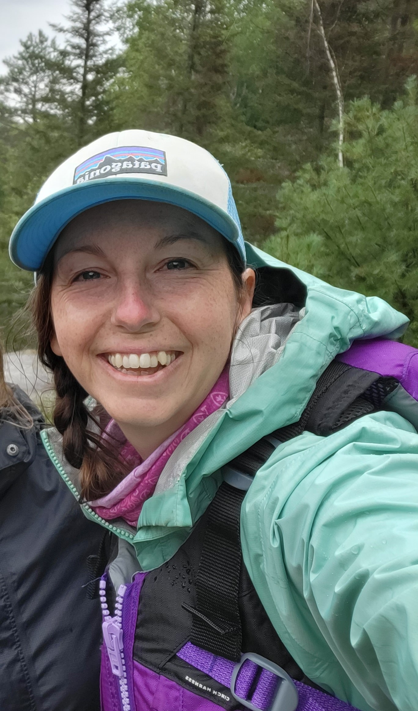 Rachel Portinga photo Photo of Rachel smiling outdoors in rain coat, life jacket, and cap.