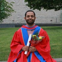 Dr. Salimur Choudhury on what appears to be a graduation day. He is wearing his robe and holding a beautiful bouquet