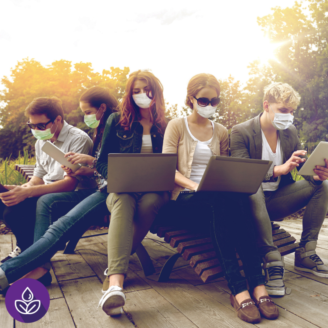 Group of students seated, wearing masks and using devices