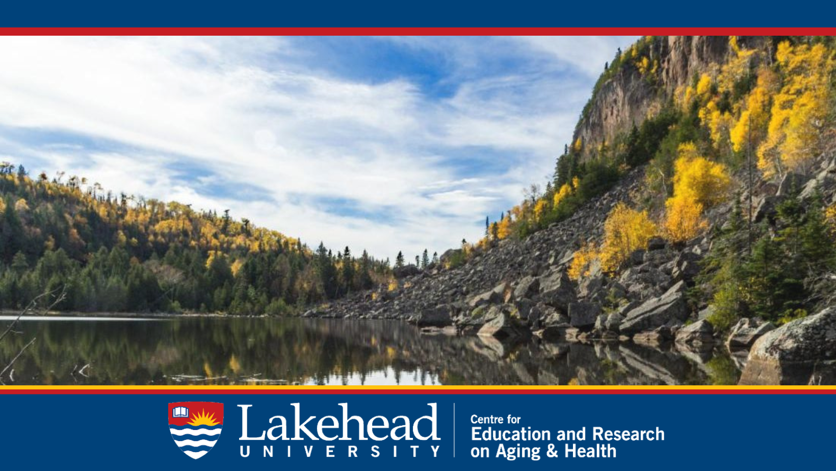 Hills of rock lead into a lake set against a background of trees with changing leaves