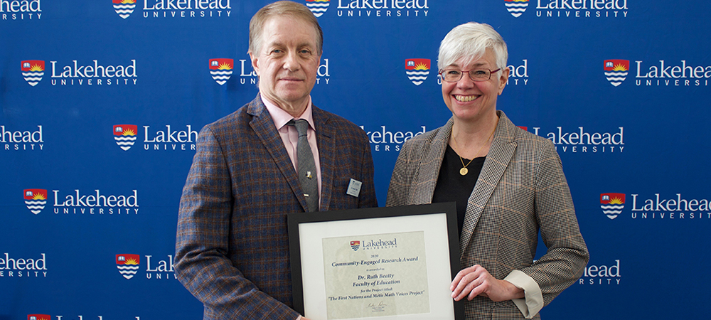 Man presents black framed award to woman during award ceremony