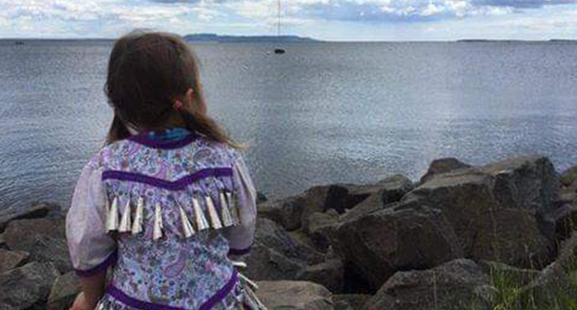 Girl sitting on rocks gazing out at water