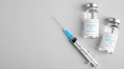 Vials with coronavirus vaccine and syringe on light background, flat lay