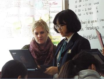 This is a picture of a teacher looking at a computer with a student