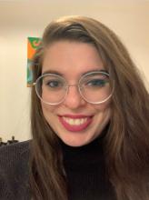 Smiling woman in long light brown hair and wearing glasses.
