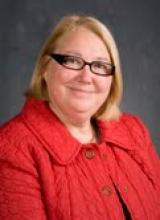 Dr Sylvane Filice blond hair , blue eyes, glasses, wearing a red jacket