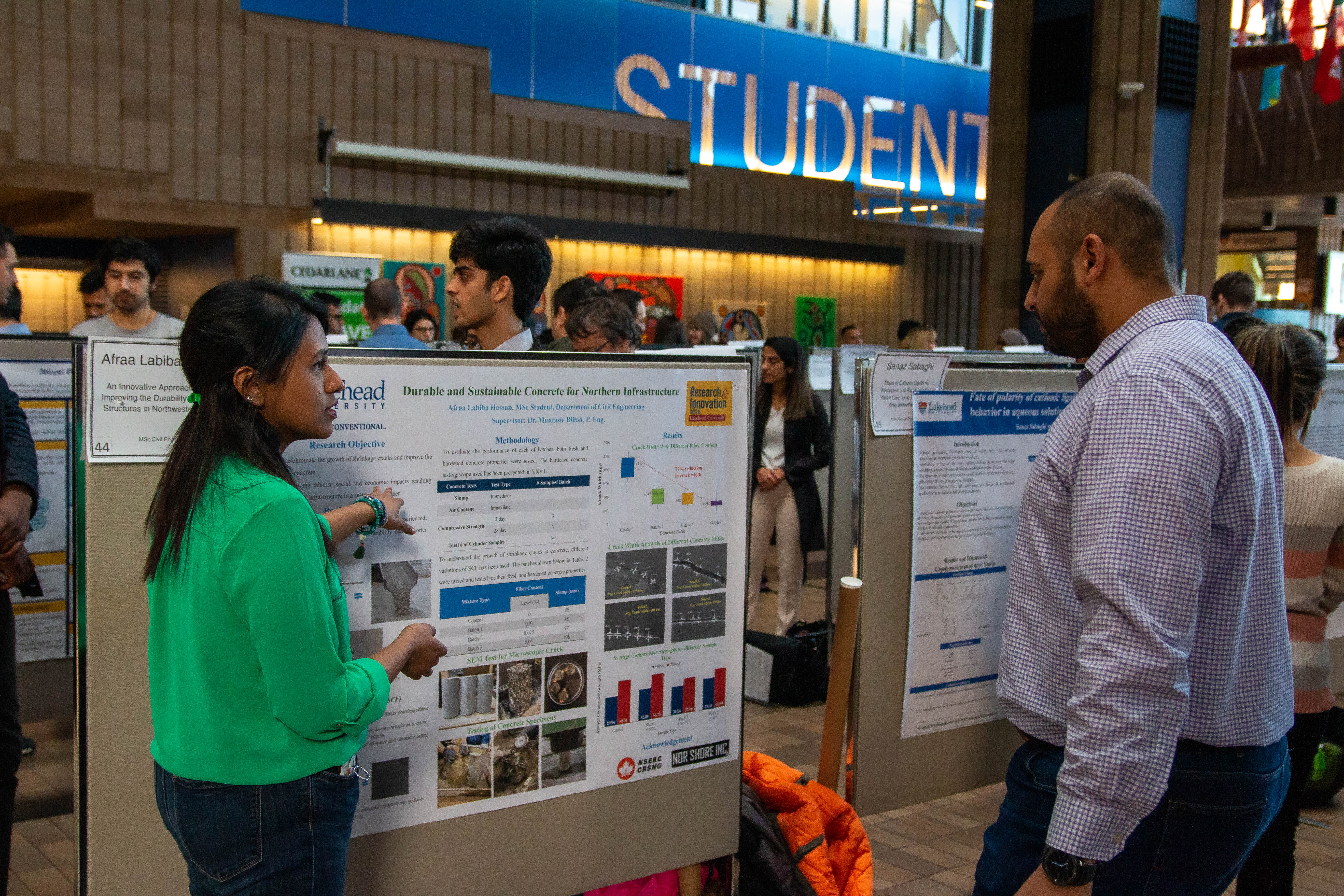 Photo of Graduate Student and Faculty Member Discussing Poster in the Lakehead University Agora