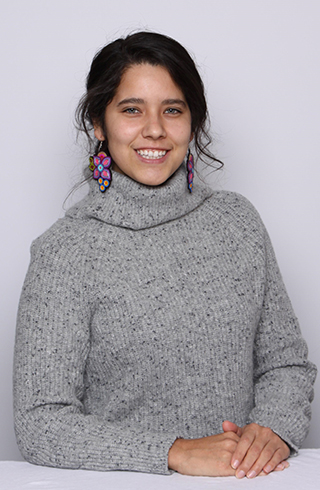 Cassandra smiling for the camera infront of a neutral grey background