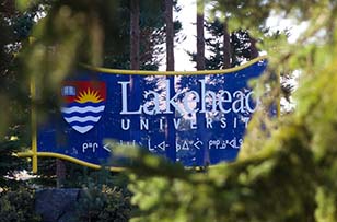 The sign at the entrance of Lakehead Thunder Bay surrounded by beautiful trees and flowers