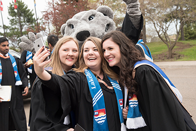 Students enjoying a selfie on graduation day with Wolfie!
