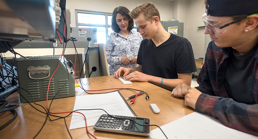 Students work in the electrical lab with assistance from a professor