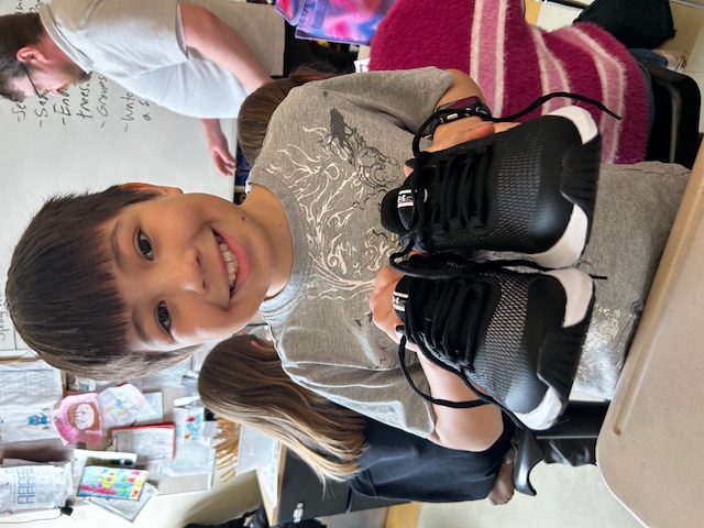 An Achievement Program student holds a new pair of running shoes
