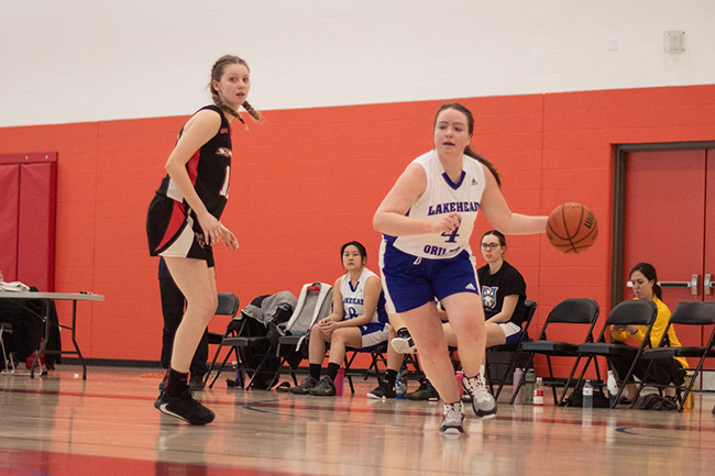 A female basketball player dribbles a basketball down the court