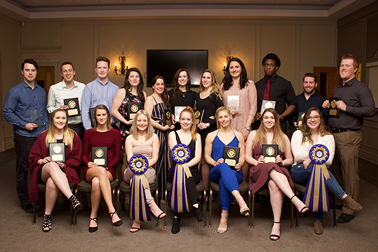 A group of 18 young men and women proudly hold up their plaques for MVP and Rookie of the Year