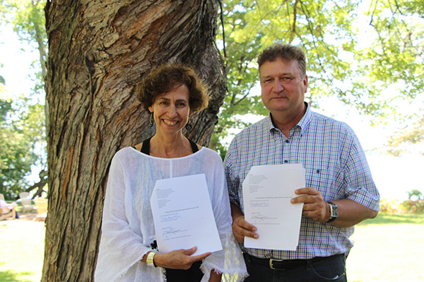 Couchiching Institute on Public Affairs President Dr. Rima Berns-McGown and Lakehead University President and Vice-Chancellor Dr. Brian Stevenson display their newly-signed Memorandum of Understanding documents following a signing at the Institute's annual Summer Conference at Geneva Park.