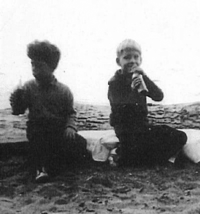 Back and white photo of brothers Derek and David D'Alton sitting outside having a snack
